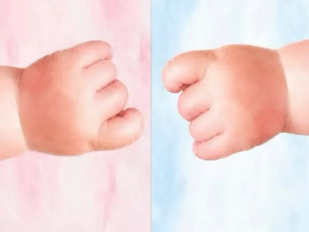 A baby's two small hands on pink and blue