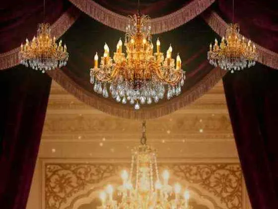 A reception stage with crystal chandeliers and velvet curtains