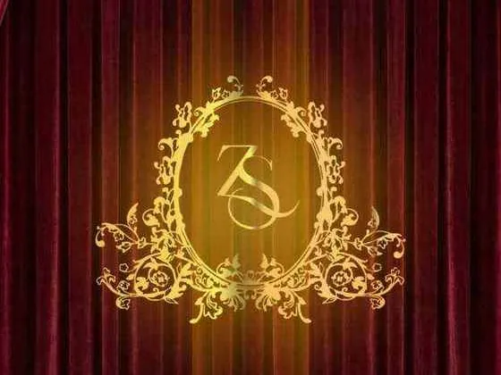 A gold monogram in an ornate frame against red velvet curtains