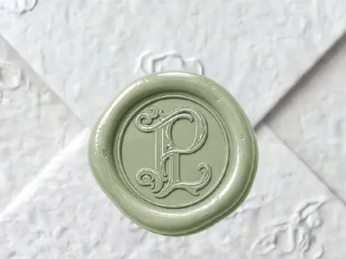 A sage wax seal on white embossed paper